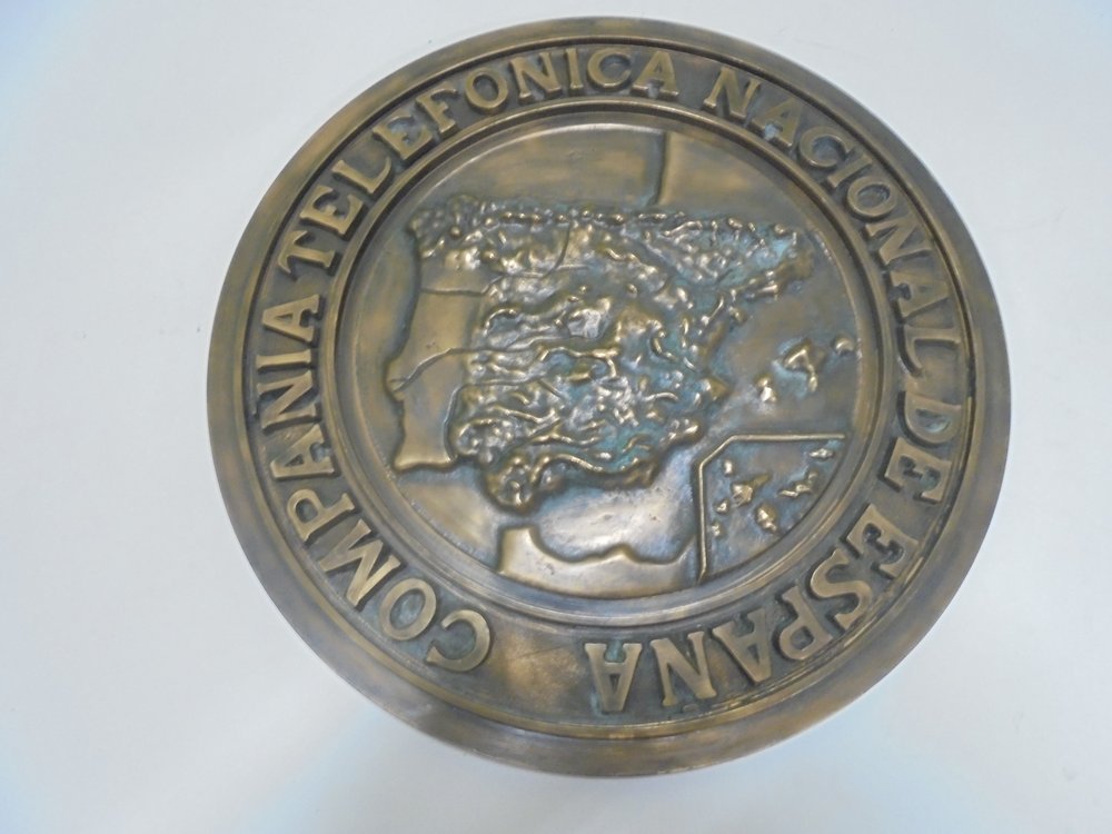 Cast bronze plaque. This is the Company's first logo. These plaques were placed at the entrance to the buildings and exchanges of the Compañía Telefónica Nacional de España.