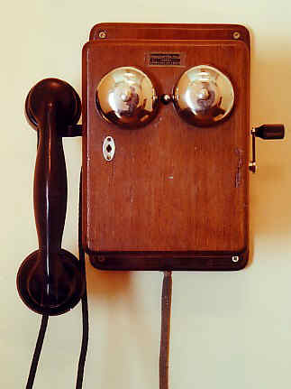 Wall-mounted telephone unit with local battery and magneto call. External buzzer with two bells located on the front. With bakelite handset.