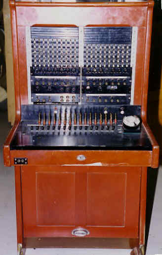 Control unit that can be linked to a manual urban control unit with a central battery or to an automatic one. Model built in the form of a desk with a vertical front and flat base, the lower part is narrower so that it can be placed in a seated position, in some cases they have a bar to place the feet. These models are made of red enamelled wood with the front lacquered and enamelled in black.